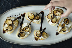 Hand holding brussels sprout crostini